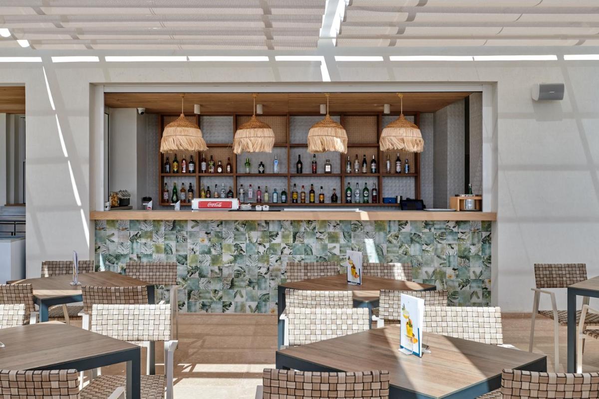 Un restaurante con mesas y sillas y un bar. en Hipotels Flamenco, en Cala Millor