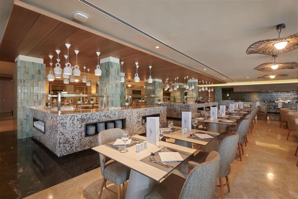 Un restaurante con mesas y sillas y un bar. en Hipotels Flamenco, en Cala Millor