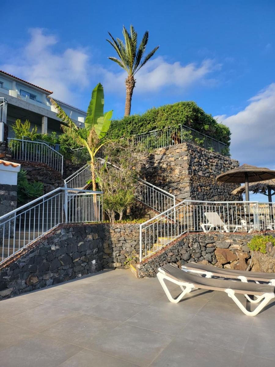 um resort com um muro de pedra e uma cadeira de praia em Hotel Roca Mar no Caniço