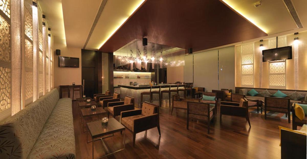a restaurant with tables and chairs and a bar at Hotel Royal Orchid Jaipur, Tonk Road in Jaipur