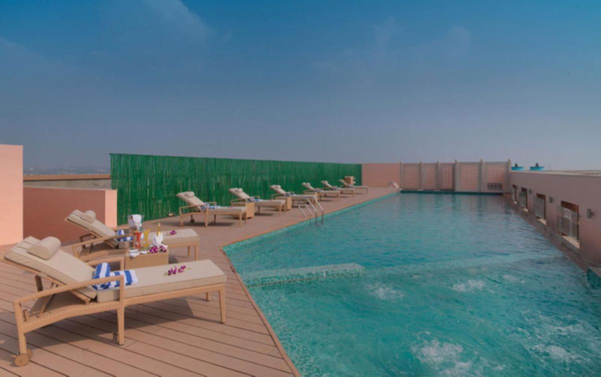 a pool on the roof of a hotel with lounge chairs at Hotel Royal Orchid Jaipur, Tonk Road in Jaipur