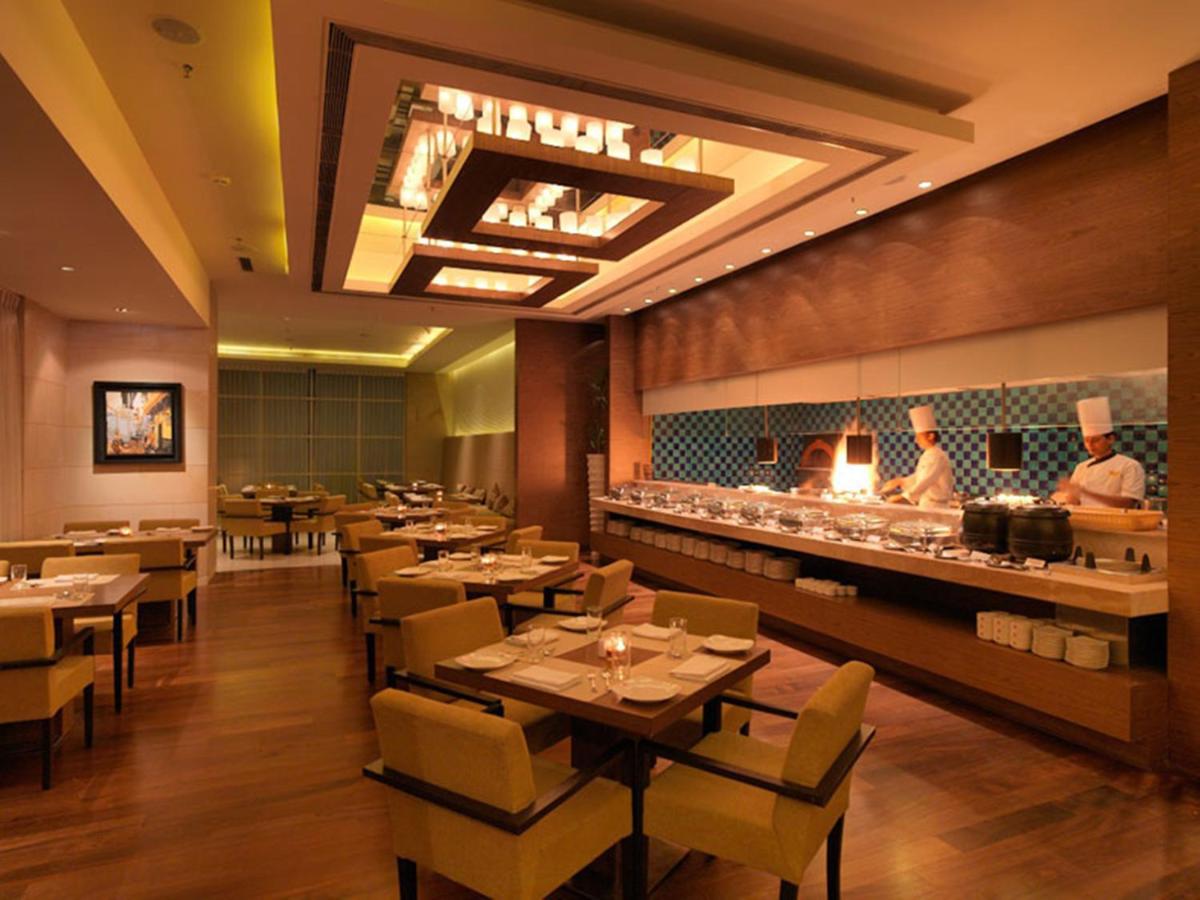 a restaurant with tables and a chef preparing food at Hotel Royal Orchid Jaipur, Tonk Road in Jaipur