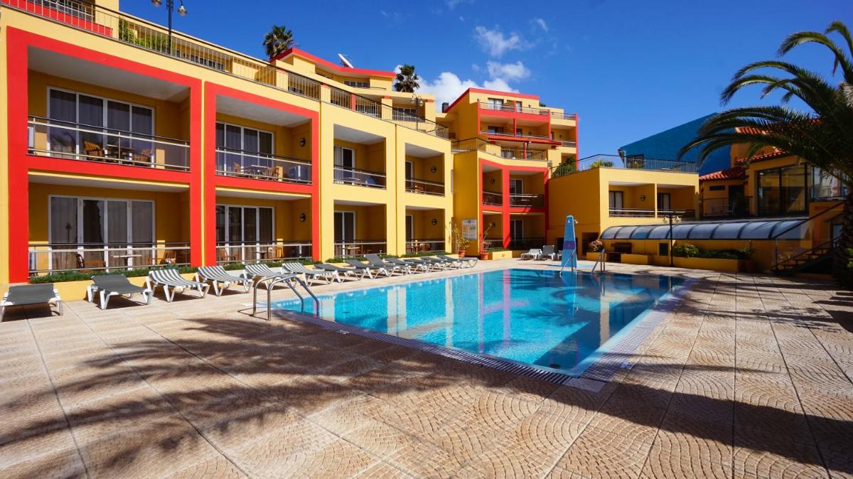 um hotel com piscina em frente a um prédio em Hotel Cais da Oliveira no Caniço