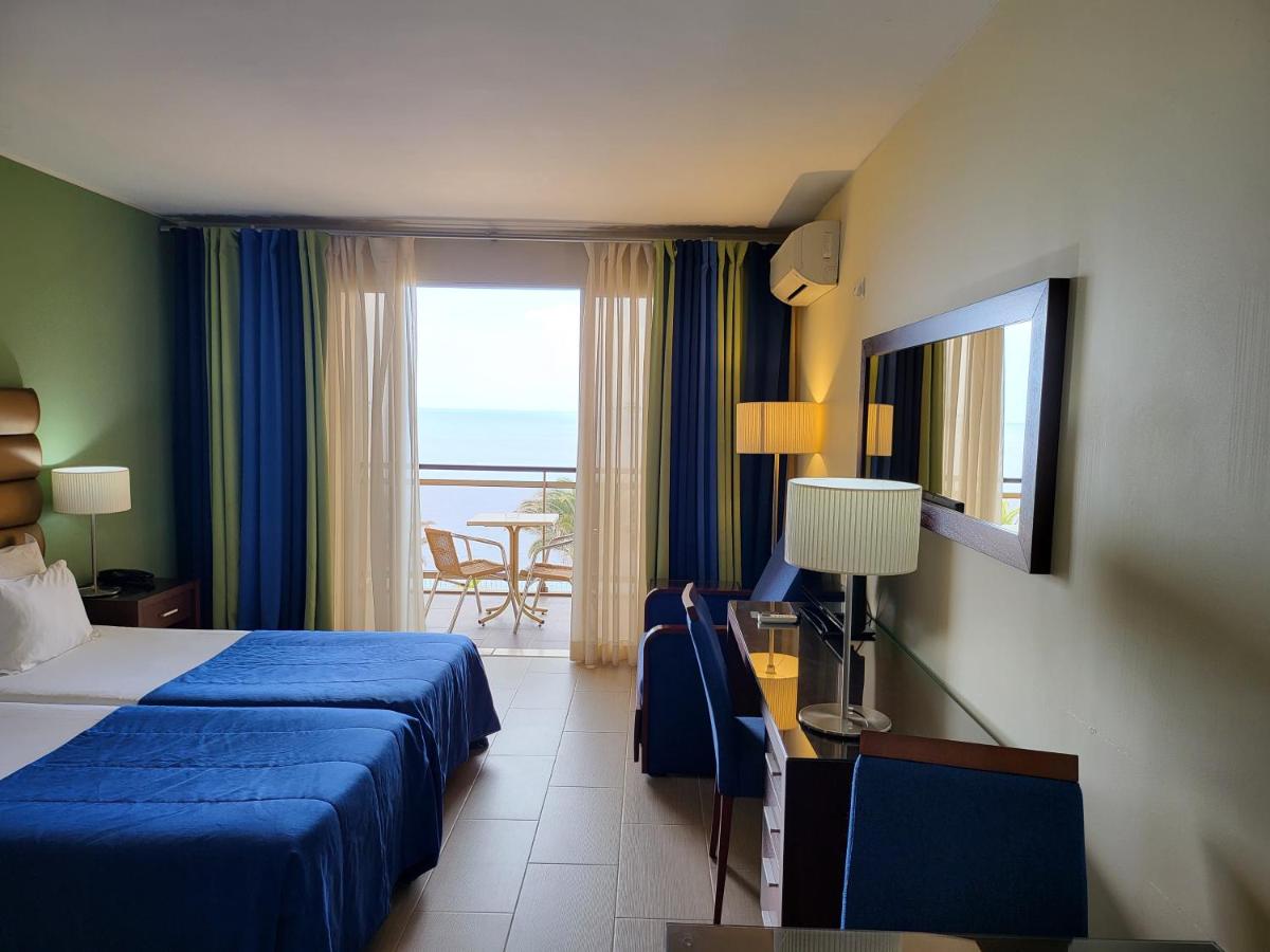um quarto de hotel com uma cama e vista para o oceano em Hotel Cais da Oliveira no Caniço mais 48 fotografias