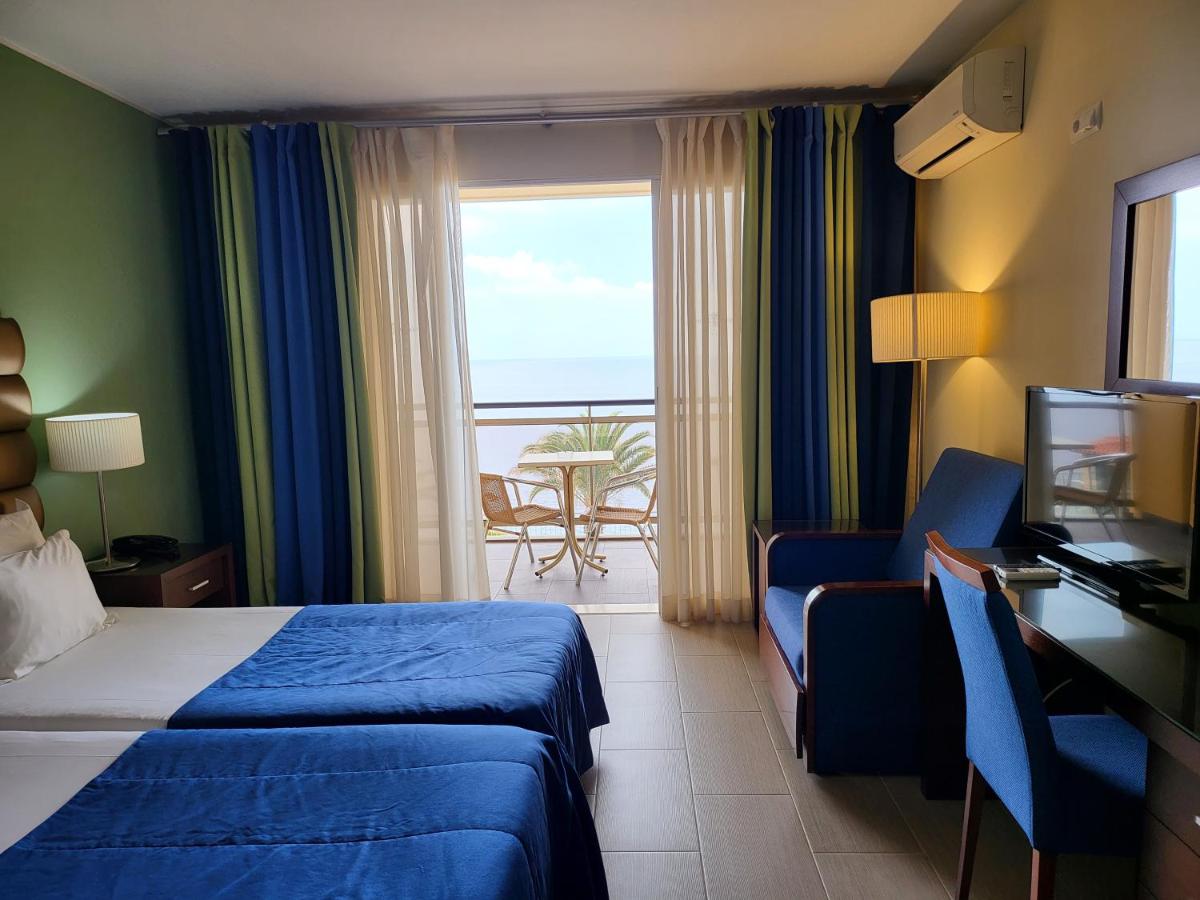 um quarto de hotel com uma cama, uma cadeira e uma janela em Hotel Cais da Oliveira no Caniço