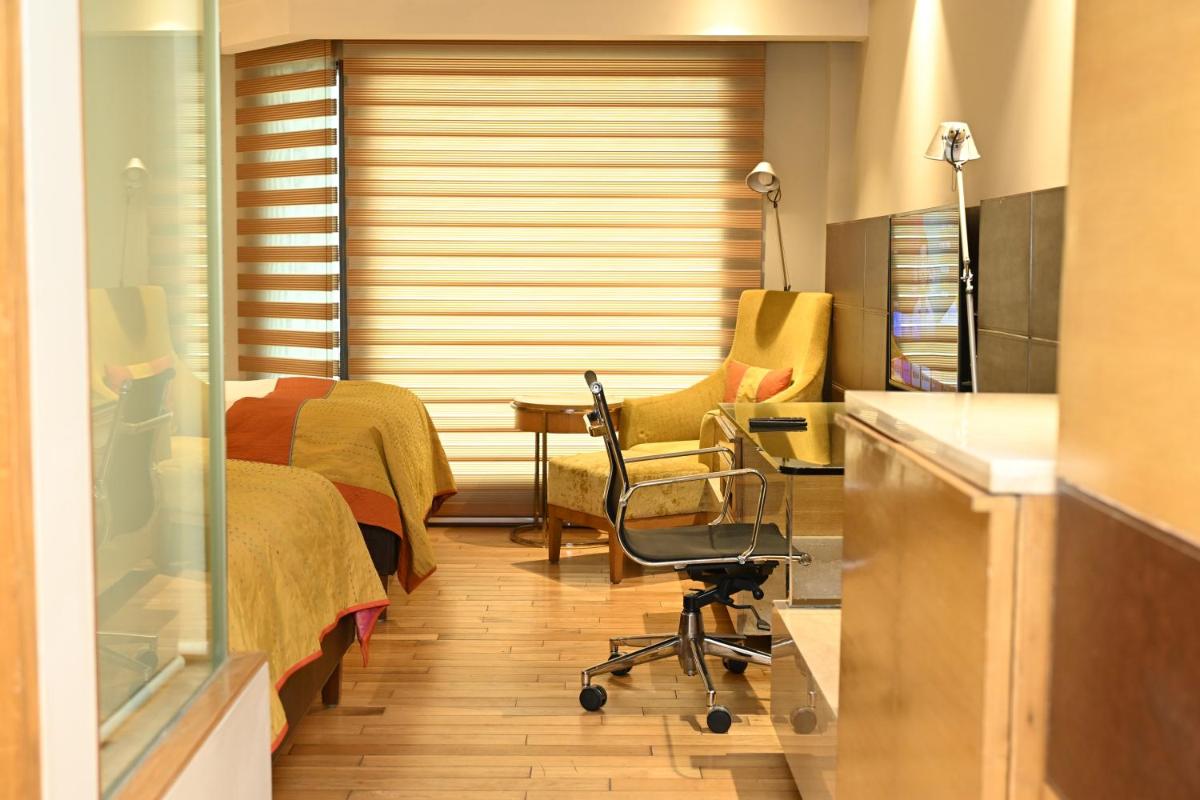 a room with a bed and a desk and a chair at The LaLiT New Delhi in New Delhi