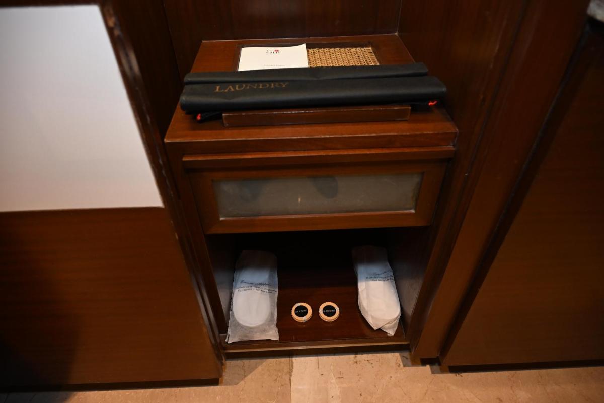 a cabinet with a book and a pair of slippers at The LaLiT New Delhi in New Delhi