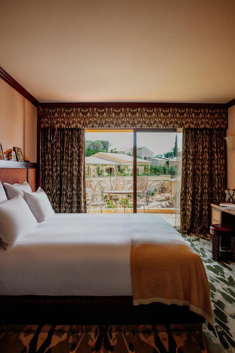 un grand lit dans une chambre avec une grande fenêtre dans l'établissement Le Mas Candille, à Mougins