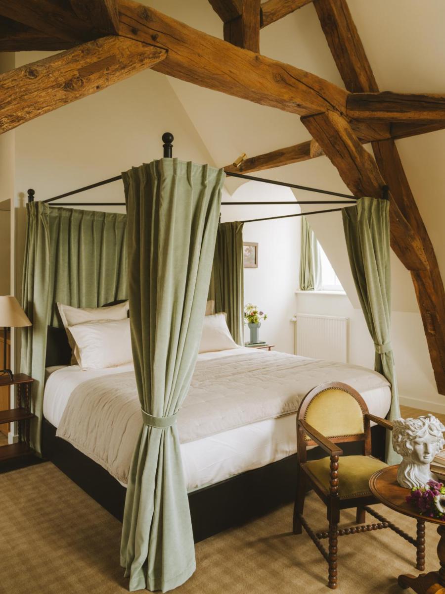 une chambre avec un lit à baldaquin et une chaise dans l'établissement Bellevigne Bourgogne, à Chambolle-Musigny
