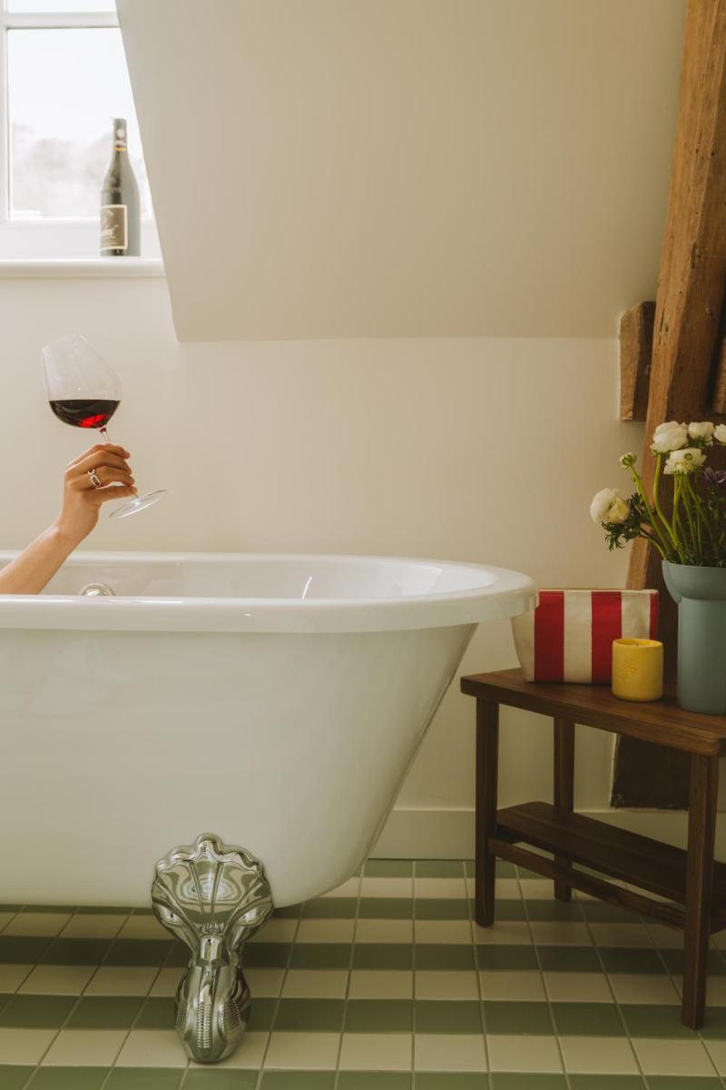 une baignoire blanche dans une salle de bain avec une personne tenant un verre de vin dans l'établissement Bellevigne Bourgogne, à Chambolle-Musigny 108 autres photos