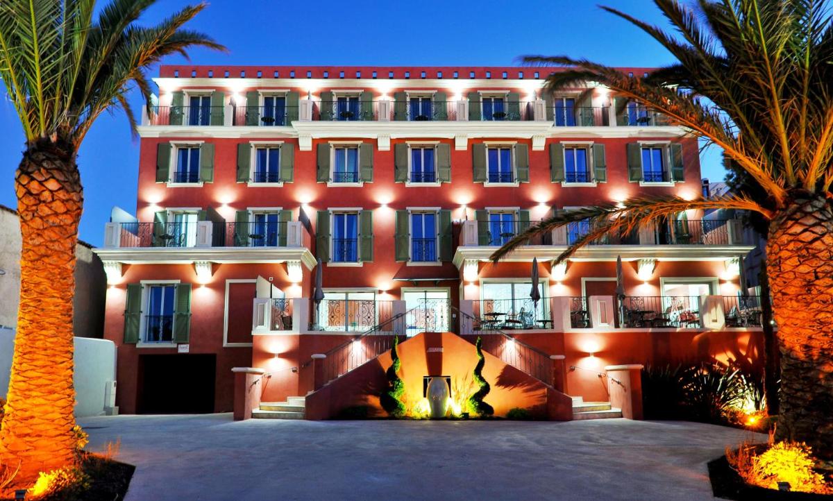 un grand bâtiment avec des palmiers devant dans l'établissement Hôtel Liberata & Spa, à LʼÎle-Rousse
