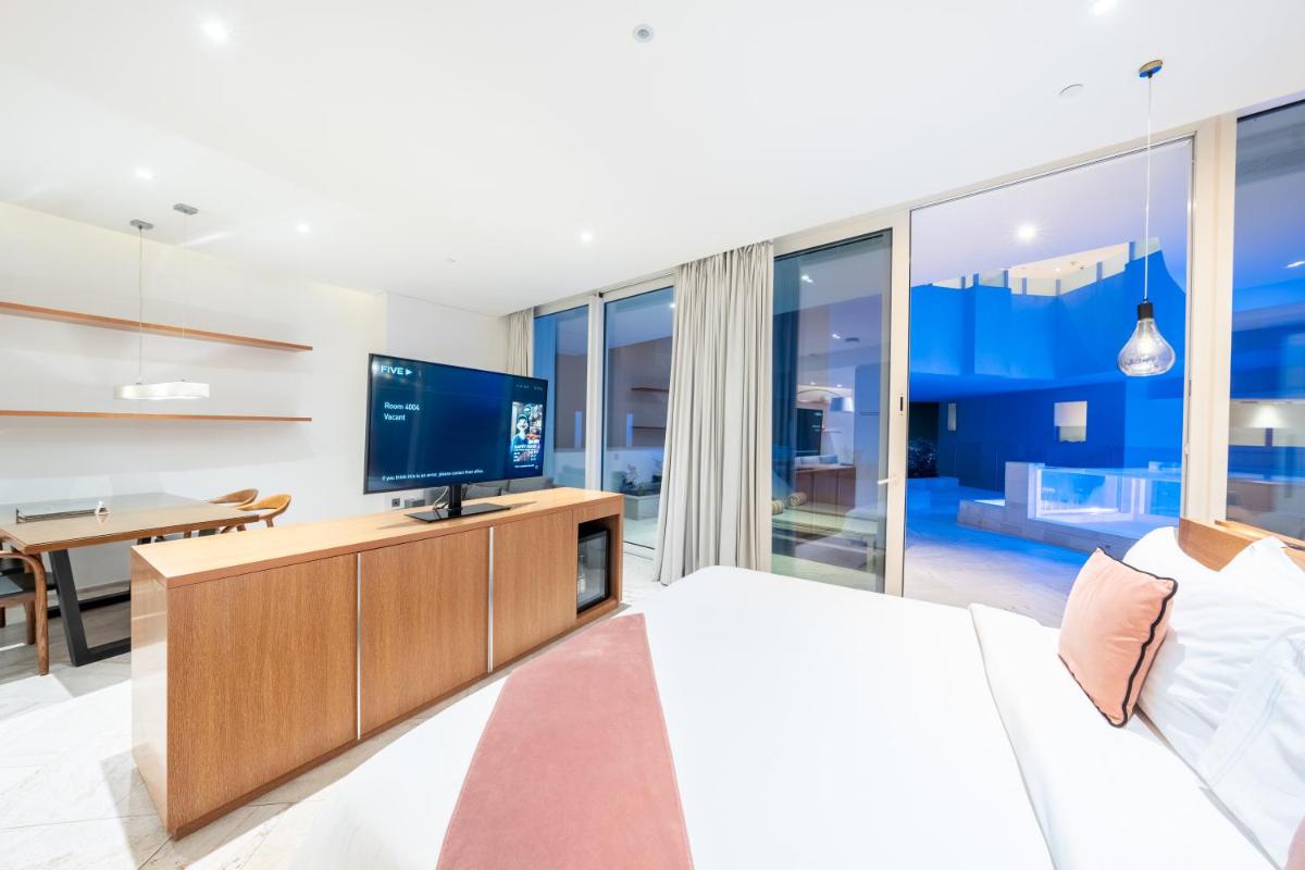 a bedroom with a bed and a tv and a table at FIVE Jumeirah Village in Dubai a bedroom with a bed and a tv and a table at FIVE Jumeirah Village in Dubai