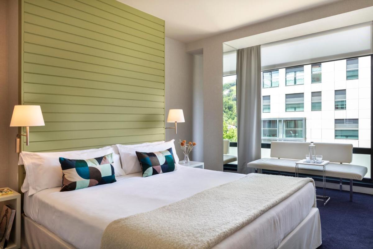 Un dormitorio con una cama grande y una ventana grande. en Hotel Miró, en Bilbao