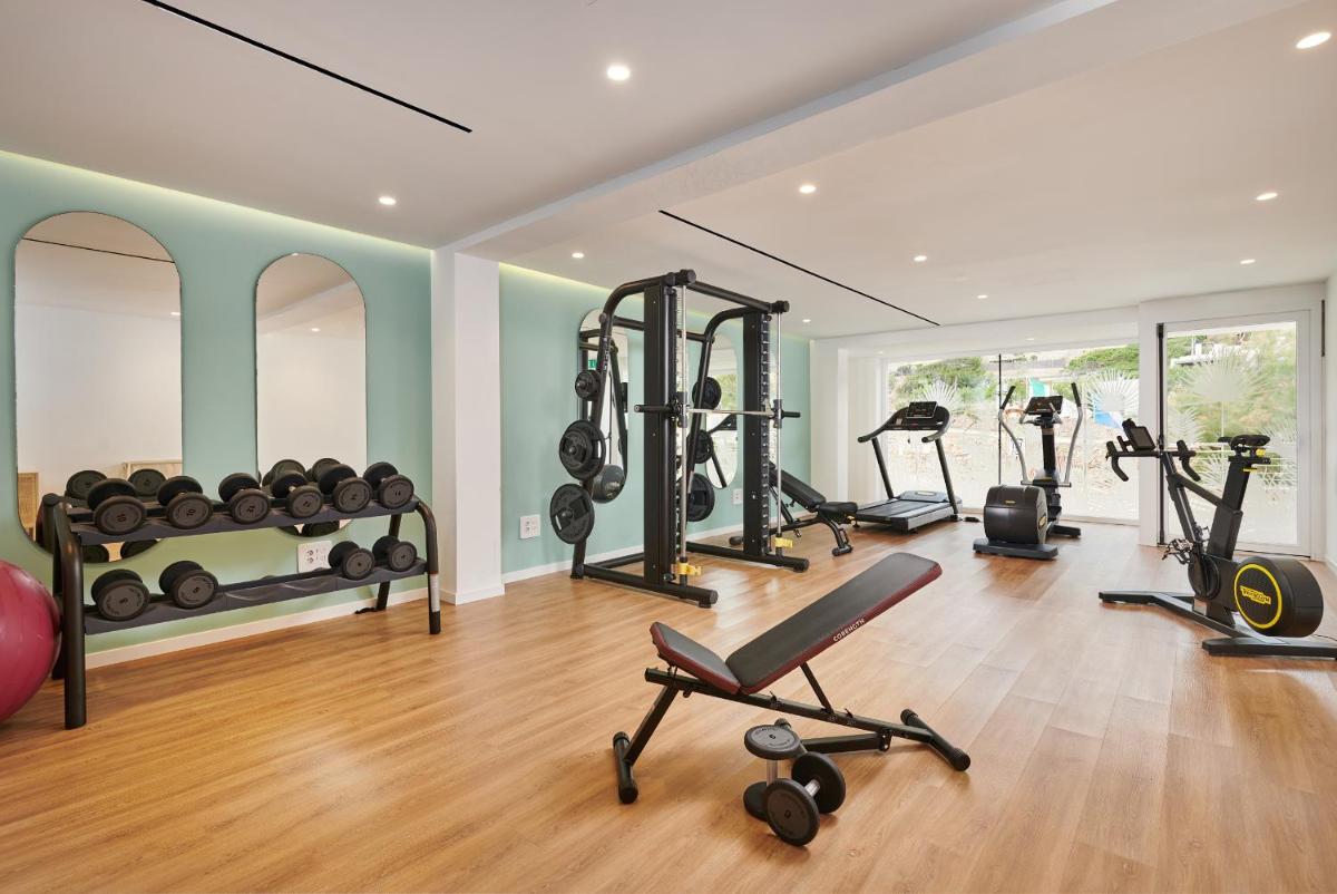 Un gimnasio con varios equipos de ejercicio en una habitación. en Grupotel Molins, en Cala de Sant Vicent