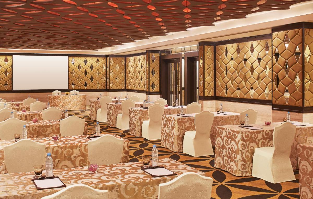 a banquet hall with tables and chairs and a screen at Taj Santacruz in Mumbai