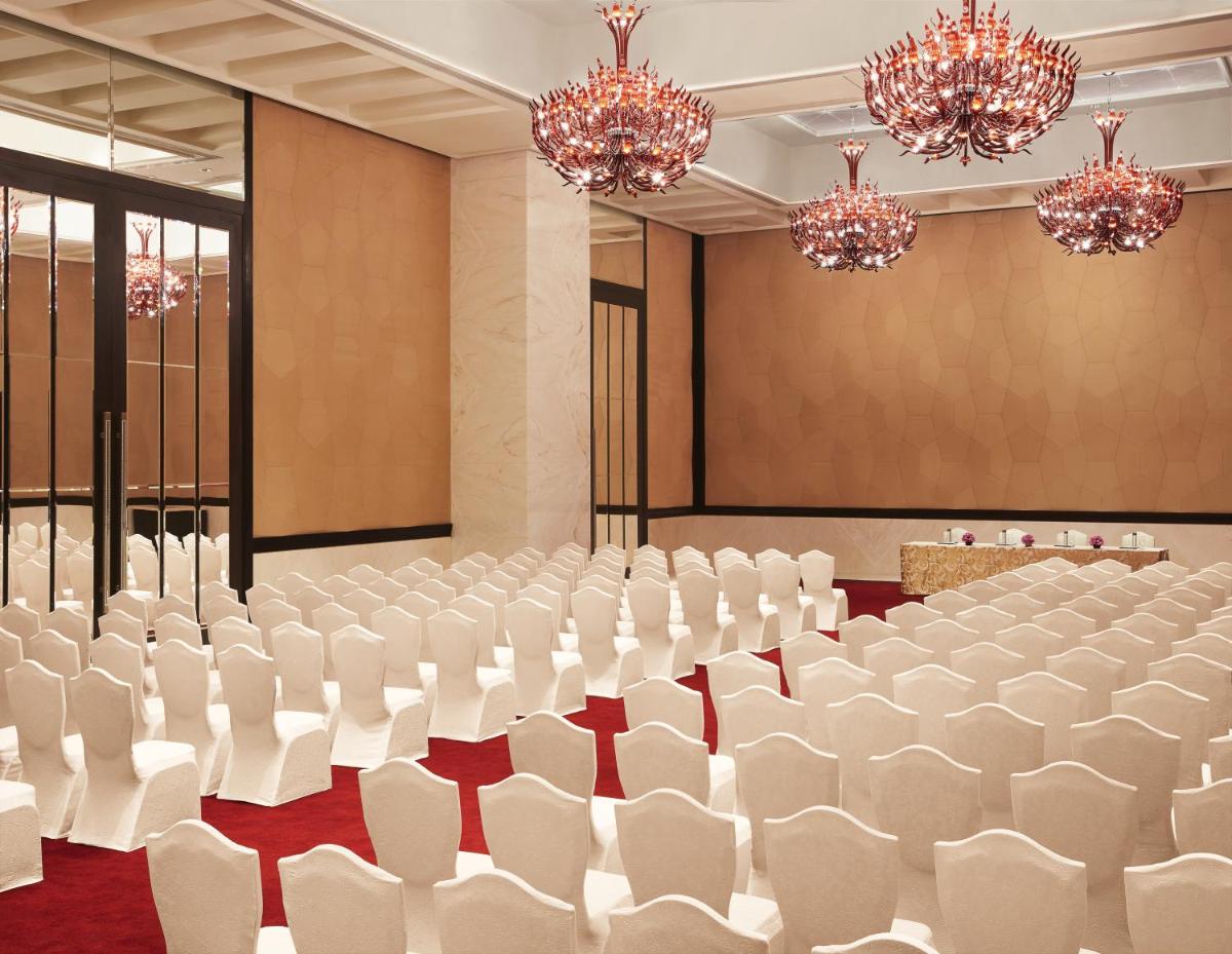 a conference room with white chairs and chandeliers at Taj Santacruz in Mumbai