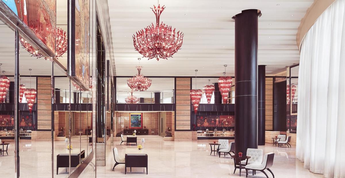 a lobby with tables and chairs and chandeliers at Taj Santacruz in Mumbai