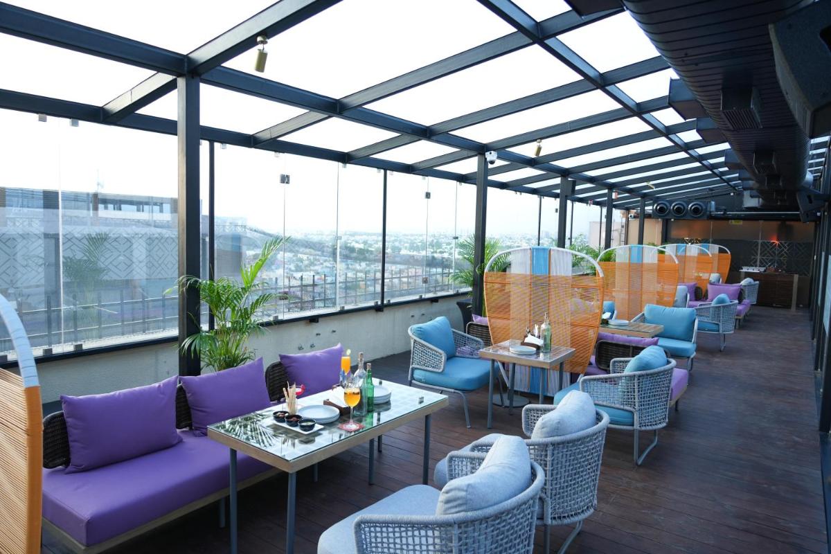 a restaurant with purple chairs and tables and windows at Hilton Chennai in Chennai