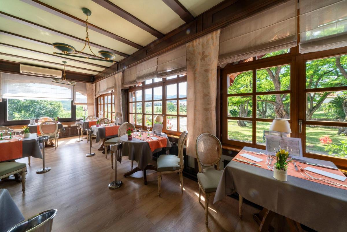 une salle à manger avec tables, chaises et fenêtres dans l'établissement Hotel Munsch Restaurant & Wellness, Colmar Nord - Haut-Koenigsbourg, à Saint-Hippolyte