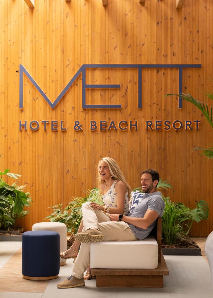 Un hombre y una mujer sentados frente a un hotel y un complejo turístico de playa. en METT Marbella Estepona, en Estepona