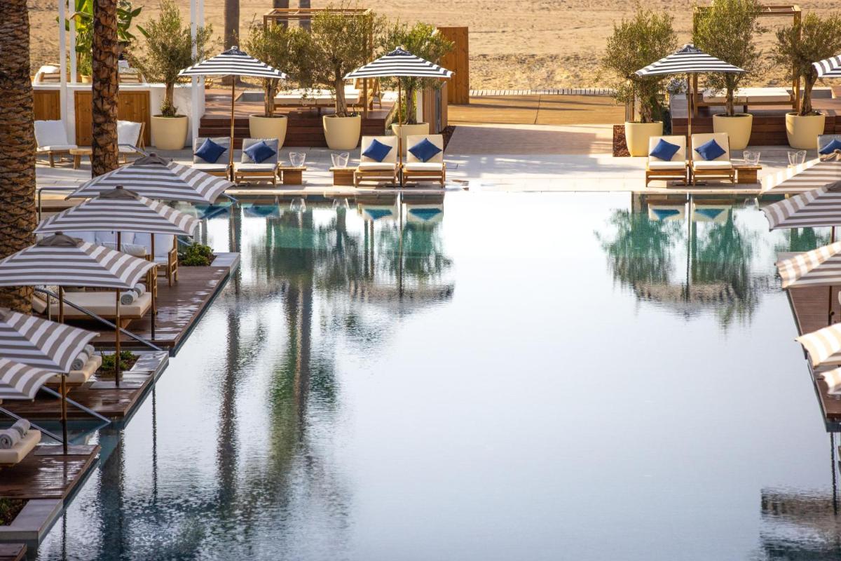 Una piscina con tumbonas y sombrillas en un resort. en METT Marbella Estepona, en Estepona 74 fotos más
