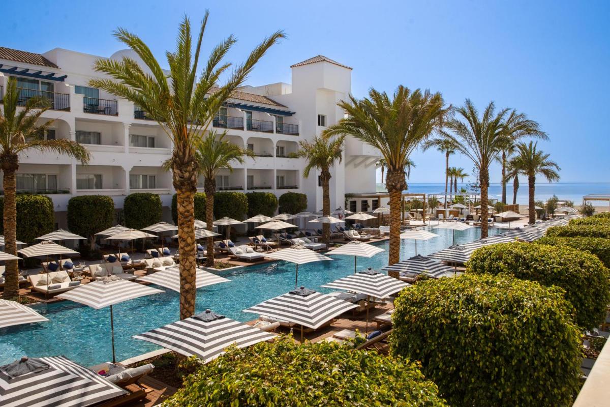 un complejo con piscina con sombrillas y palmeras en METT Marbella Estepona, en Estepona
