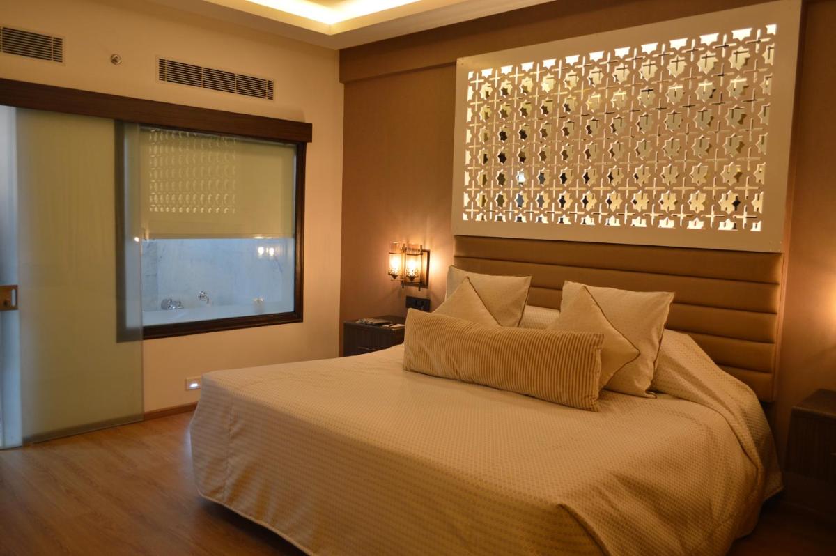 a bedroom with a large bed and a window at Hotel Clarks Shiraz in Agra