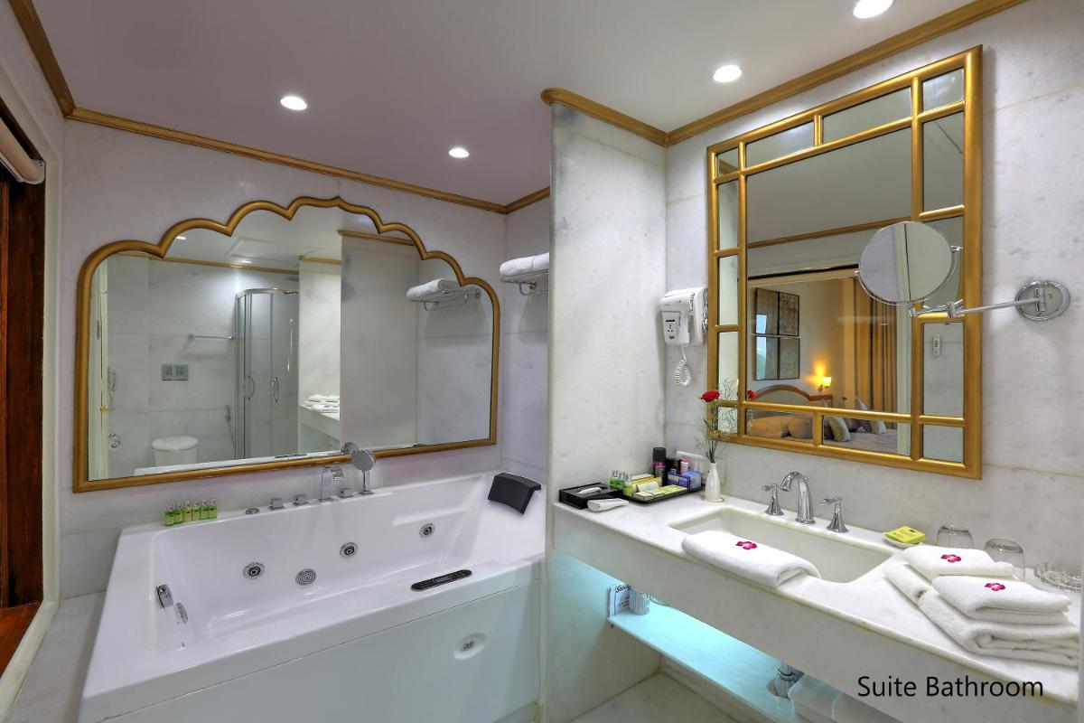 a bathroom with a tub and a sink and a mirror at Hotel Clarks Shiraz in Agra