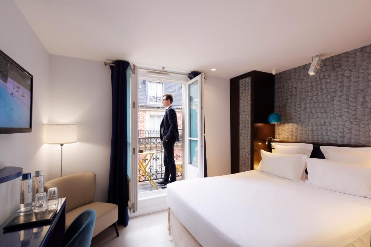un homme en costume regardant par la fenêtre d'une chambre d'hôtel dans l'établissement Hotel Eden, à Paris