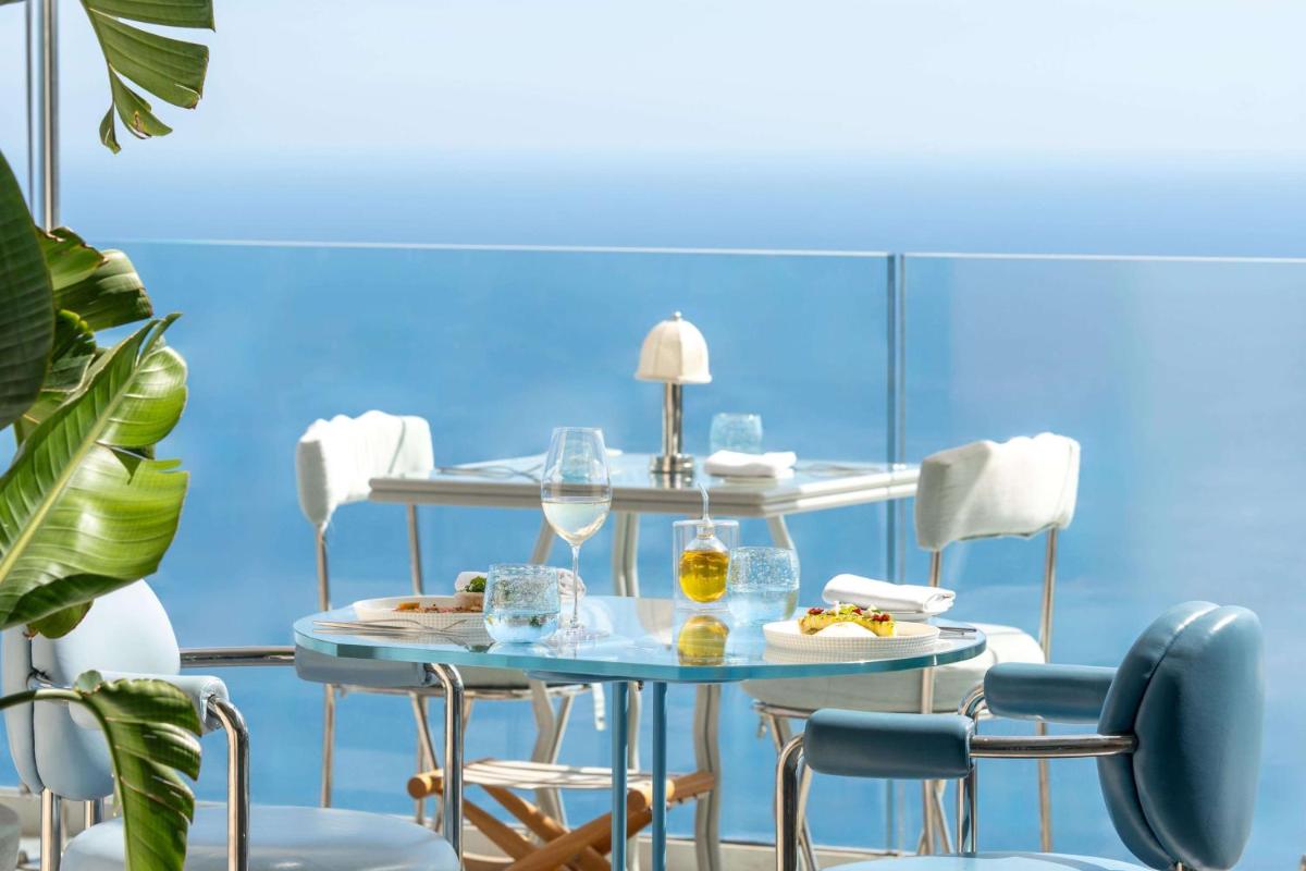 une chambre bleue avec une table et des chaises dans l'établissement The Maybourne Riviera, Maybourne, à Roquebrune-Cap-Martin