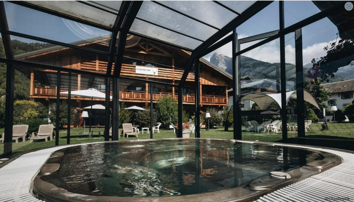 un bain à remous en face d'un bâtiment dans l'établissement Logis Hotel Gai Soleil, à Samoëns