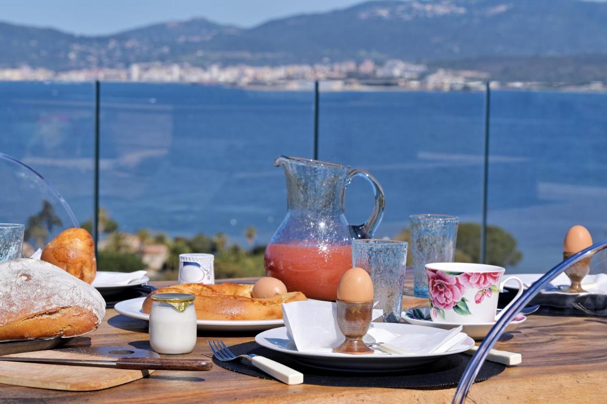 - une table avec de la nourriture et des œufs et une vue sur l'eau dans l'établissement Villa Urbana, à Porticcio