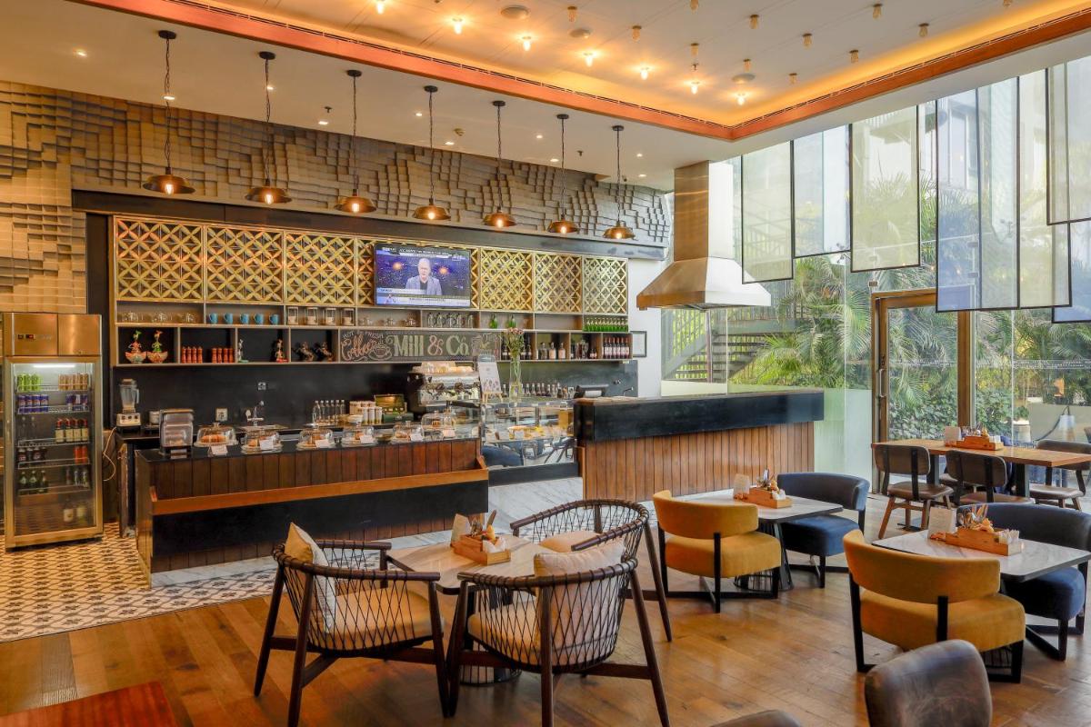 a restaurant with tables and chairs and a bar at Renaissance Ahmedabad Hotel in Ahmedabad