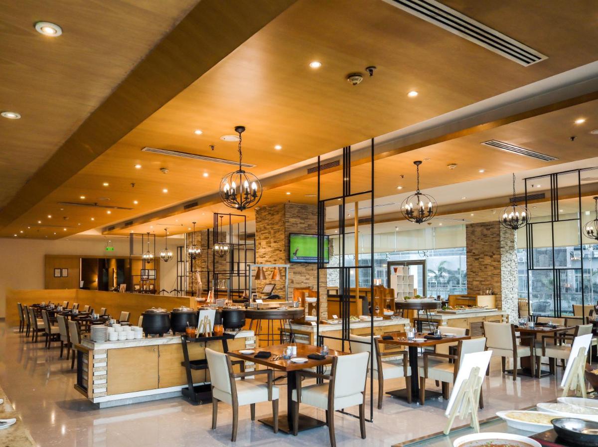 a dining room with tables and chairs in a restaurant at Renaissance Ahmedabad Hotel in Ahmedabad
