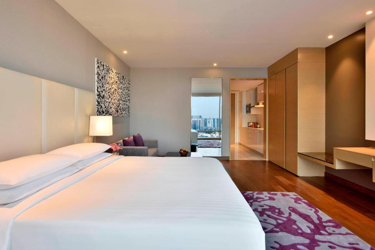 a bedroom with a large white bed and a living room at Marriott Executive Apartments Hyderabad in Hyderabad
