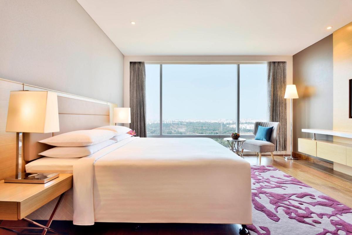 a bedroom with a large white bed and a large window at Marriott Executive Apartments Hyderabad in Hyderabad