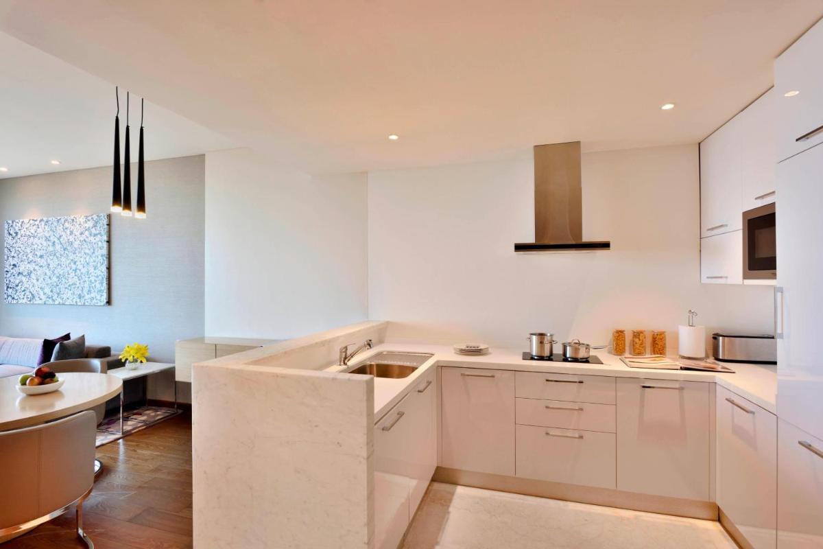 a white kitchen with a sink and a table at Marriott Executive Apartments Hyderabad in Hyderabad