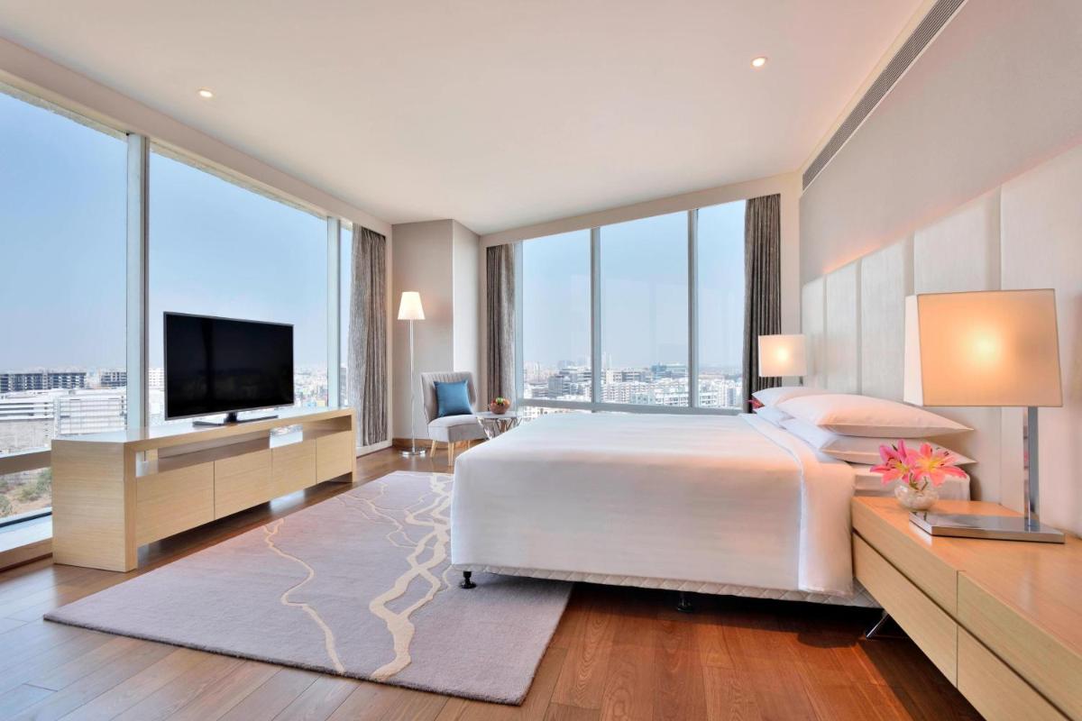 a bedroom with a large bed and large windows at Marriott Executive Apartments Hyderabad in Hyderabad