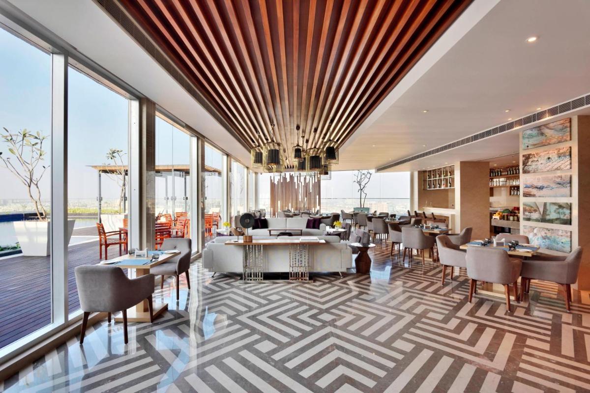 a dining room with tables and chairs and windows at Marriott Executive Apartments Hyderabad in Hyderabad