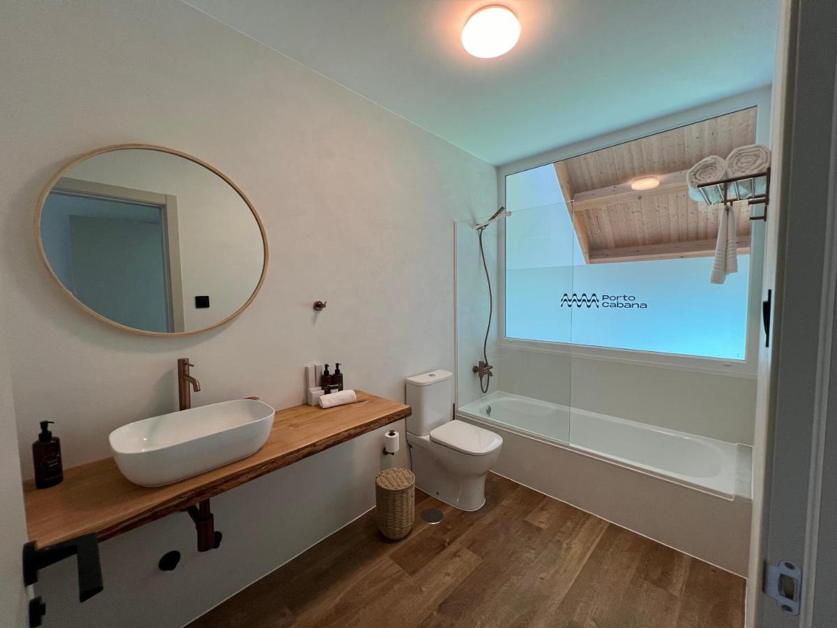 Un baño con lavabo, inodoro y espejo. en Porto Cabana by Miramar Stays, en Cabana de Bergantiños