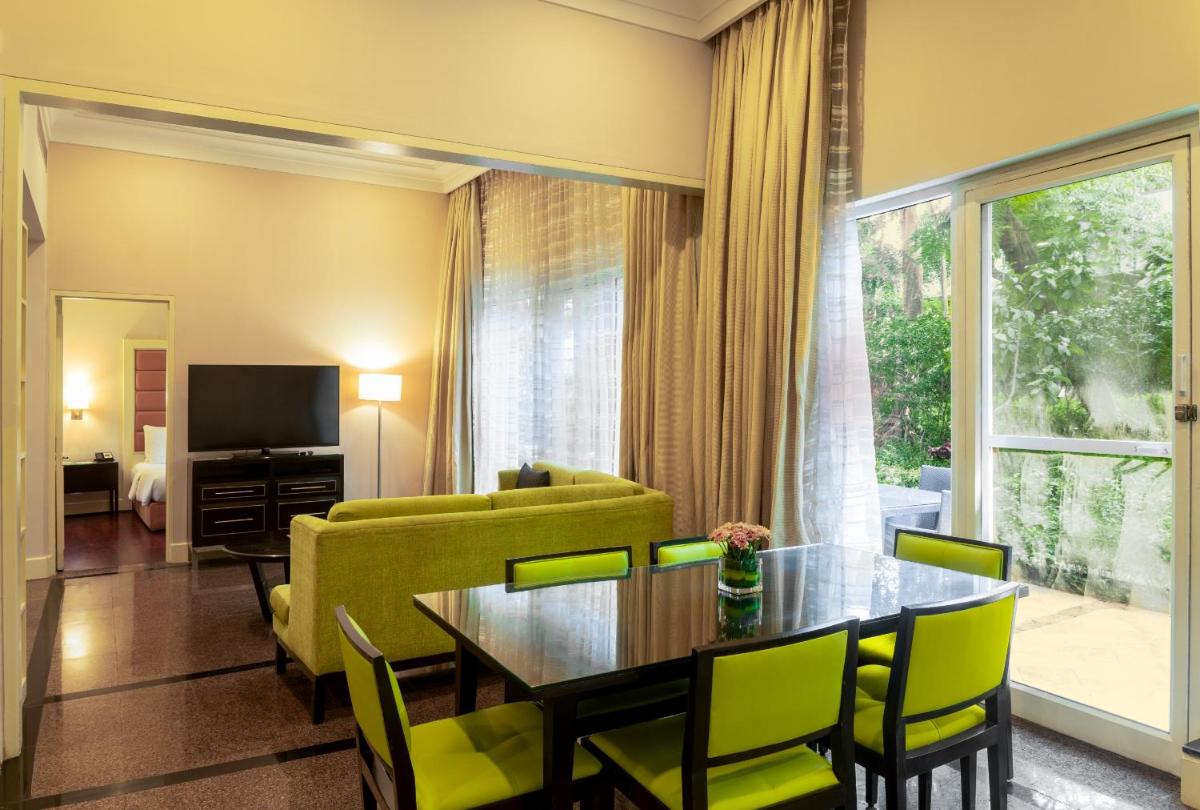 a living room with a table and chairs and a television at Marriott Executive Apartment - Lakeside Chalet, Mumbai in Mumbai