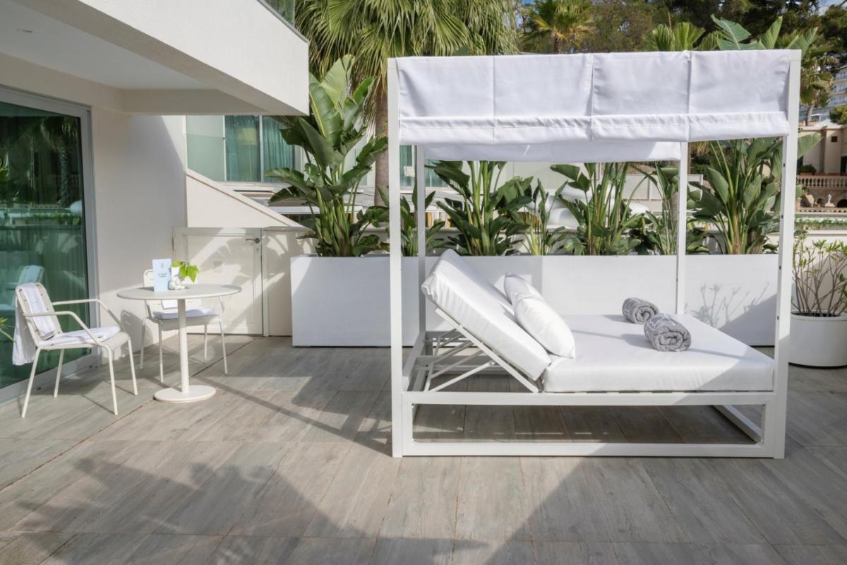 un porche con una cama blanca y una mesa en The Donna Portals, en Portals Nous