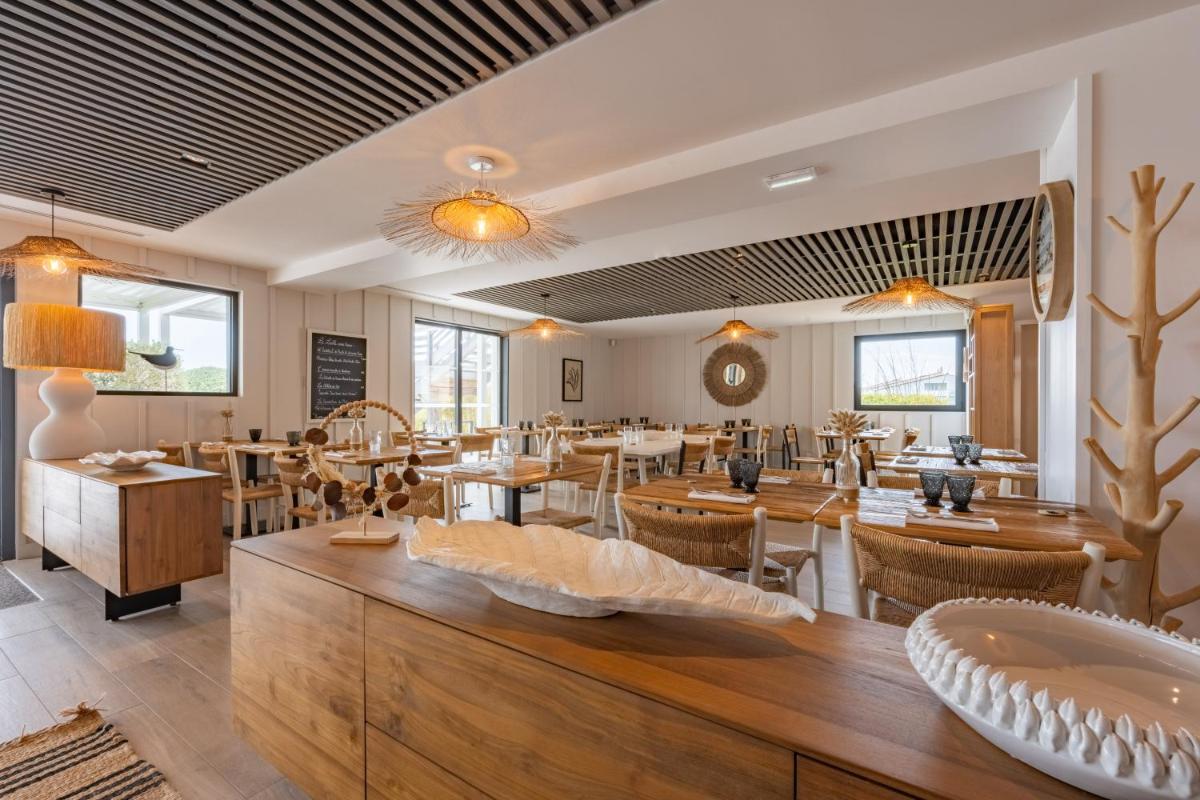 un restaurant avec des tables et des chaises en bois et une salle dans l'établissement Hôtel Atalante - Relais Thalasso & Spa, à Sainte-Marie de Ré