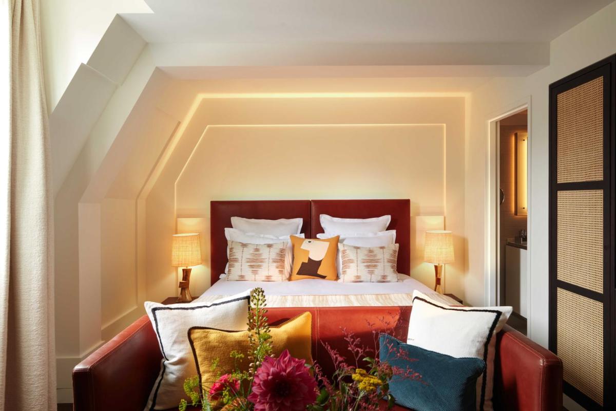 une chambre avec un lit et un canapé avec des oreillers dans l'établissement Hotel La Villa Saint Germain Des Prés, à Paris