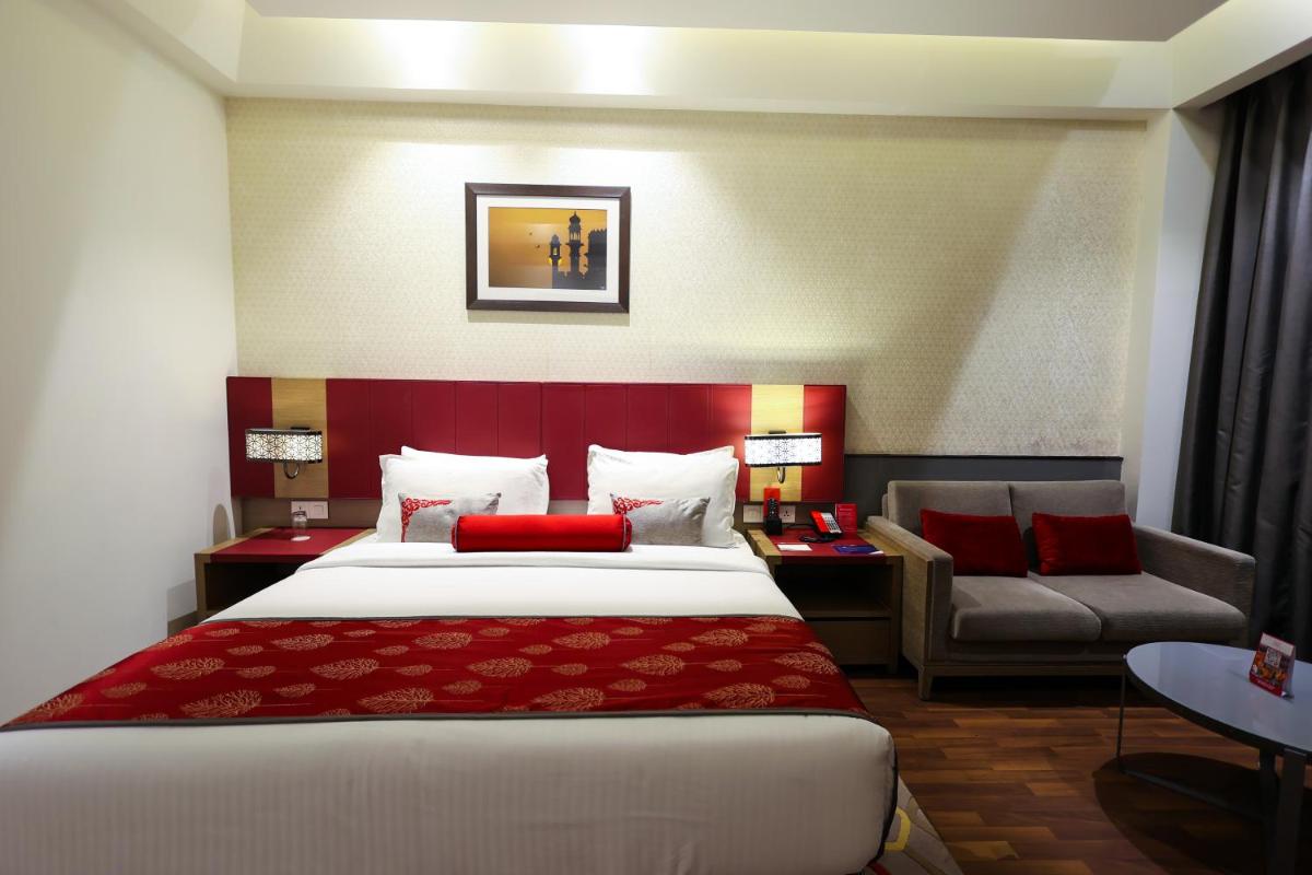a hotel room with a large bed and a couch at Ramada Plaza by Wyndham Lucknow in Lucknow