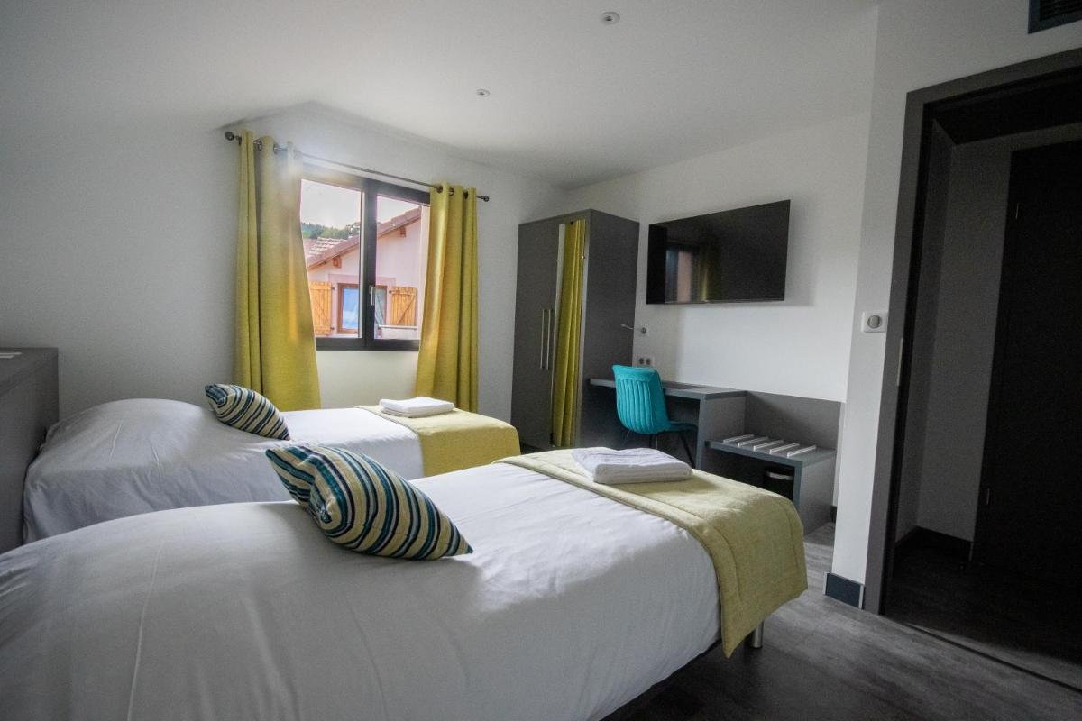 une chambre d'hôtel avec deux lits et une fenêtre dans l'établissement Logis Hôtel Le Régal & Spa, à Saint-Dié-des-Vosges 56 autres photos