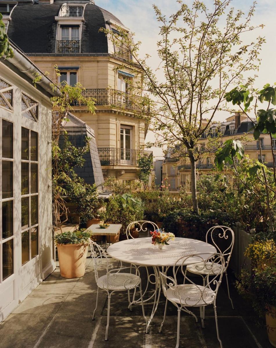 un patio avec une table et des chaises et un bâtiment dans l'établissement Château Voltaire, à Paris 74 autres photos