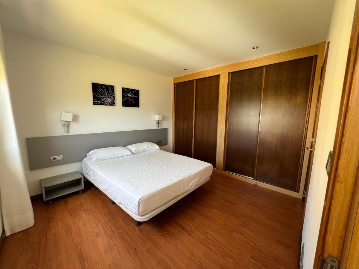 Un dormitorio con una cama blanca y suelos de madera. en Porto Cabana by Miramar Stays, en Cabana de Bergantiños