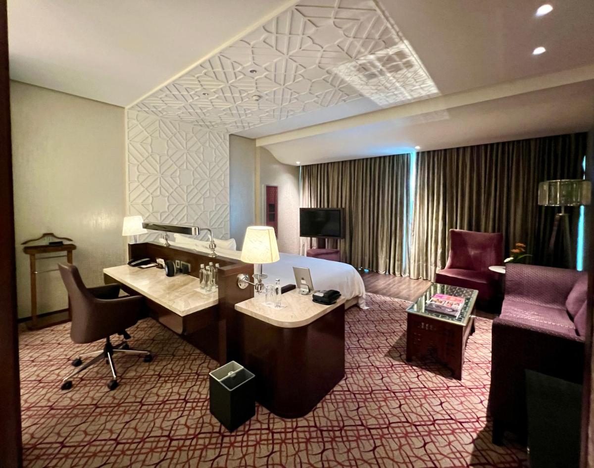 a hotel room with a bed and a desk and chairs at ITC Kohenur, a Luxury Collection Hotel, Hyderabad in Hyderabad