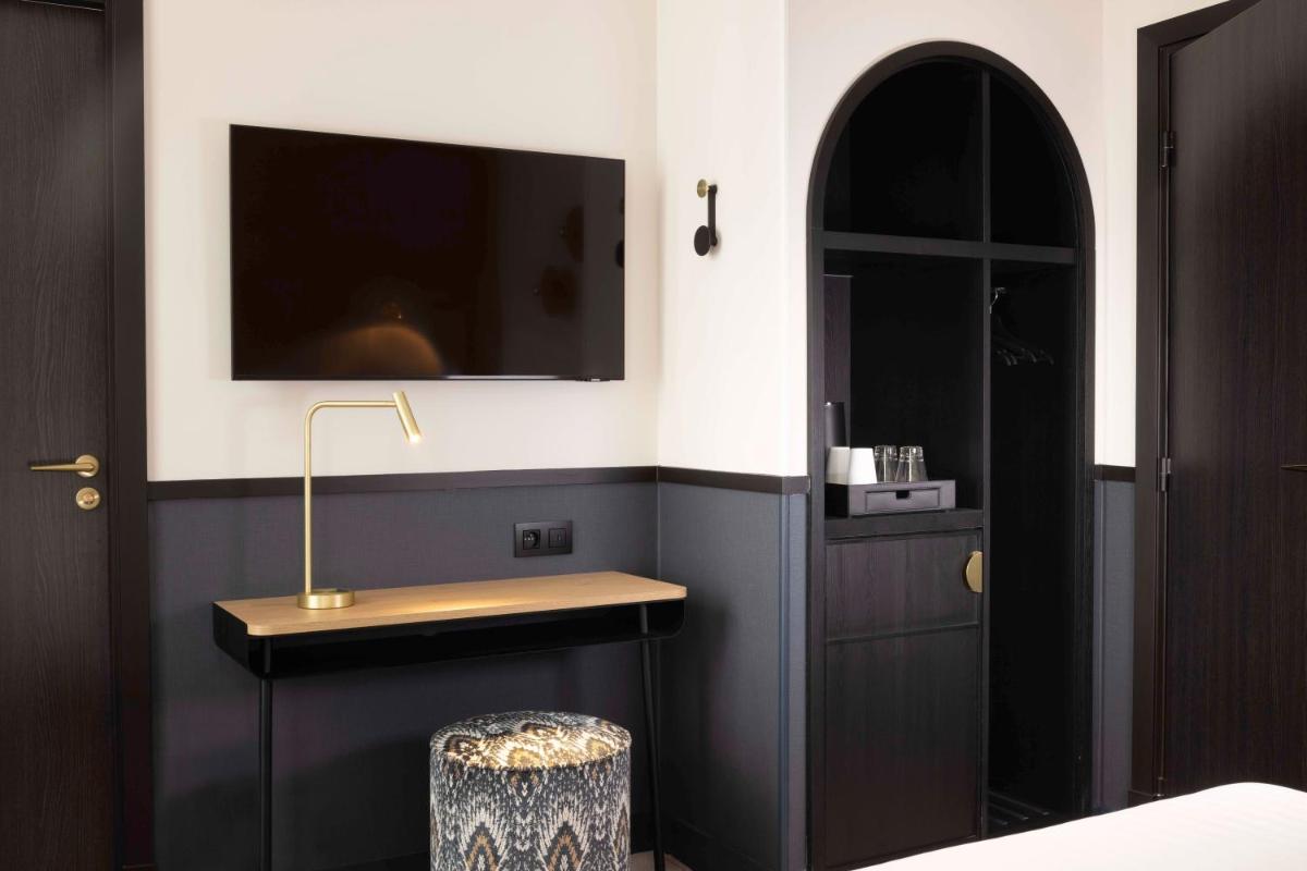 une chambre avec un lit et une télévision sur un mur dans l'établissement Hotel Grand Coeur Latin, à Paris